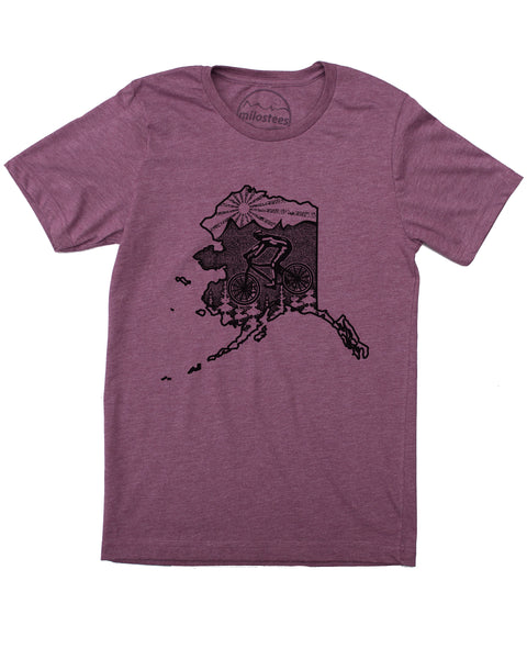 Plum Alaska cycling t-shirt featuring a mountain biker and cedar trees. Screen-printed design with mountain logo and setting sun.