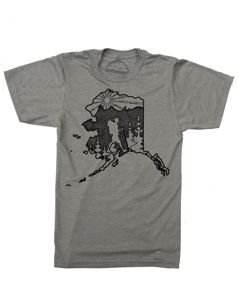 Hike Alaska shirt with original hand screen printed illustration of a hiker in the state of Alaska complete with trees, mountains and setting sun. Print on an army green tee in a cotton, polyester blend. $21.99, free shipping in USA. Elevate the Day! 