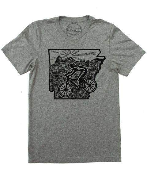 Bike Arkansas print, cyclist riding the bottom of the state with rolling hills and setting sun infilling the top of AR. Black screen print on a cotton, polyester tee in a grey hue