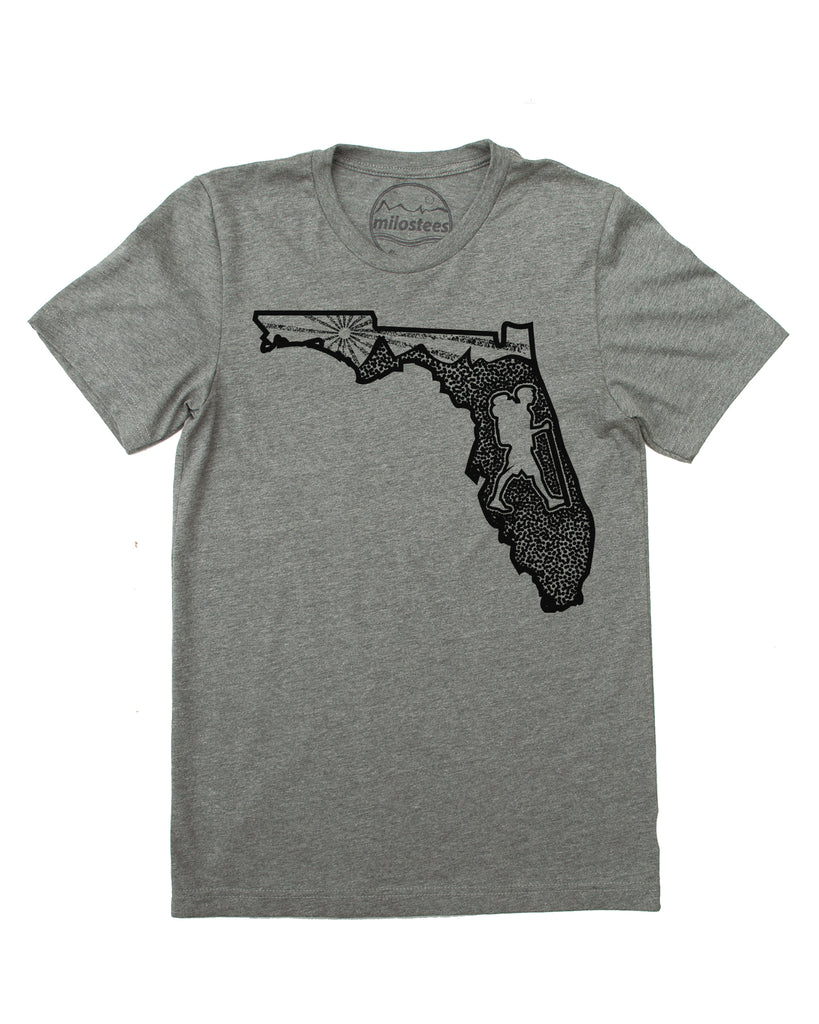 Graphic illustartion of a hiker in state of Florida, complete with rolling hills and setting sun all infill the state. Black ink on a cotton, polyester blend in a grey hue. $21.99, free shipping in USA