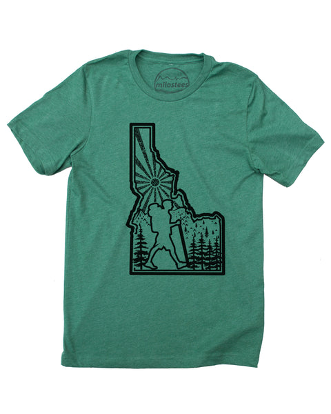 Hike Idaho shirt, green color, original hand screen printed graphic of a hiker hiking inside the State outline of Idaho, infilled with sun mountains and trees. $21.99, free shipping in the USA.