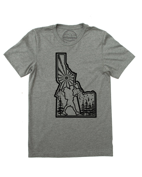 Hike Idaho shirt, grey color, original hand screen printed graphic of a hiker hiking inside the State outline of Idaho, infilled with sun mountains and trees. $21.99, free shipping in the USA.