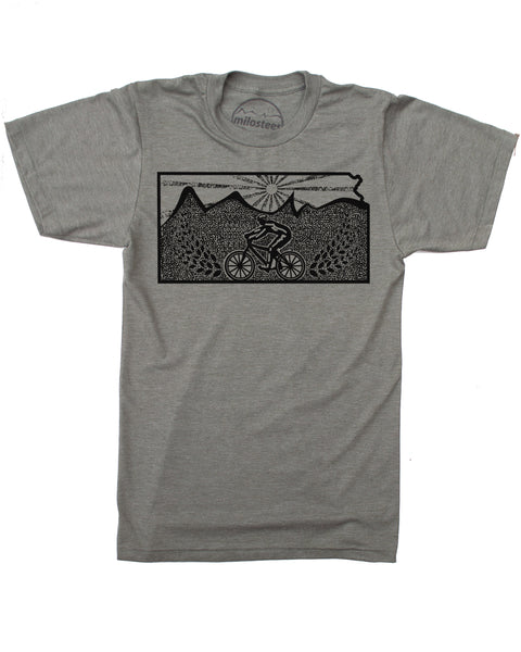 Heather army green t-shirt with graphicBlack ink illustration of a cyclist riding a bicycle across rolling hills under a setting sun, with two stalks of wheat flanking the cyclist on either side. Available in sizes small, medium, large, extra large, and double extra large.