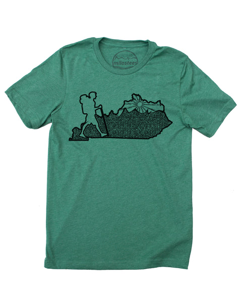 Kentucky home tee, hand screen print of a hiker in KY, complete with rolling hills and setting sun all of which infill the Blue Grass state.  Cotton, polyester blend by Bella + Canvas in a green hue. $21.99, free shipping in USA. 