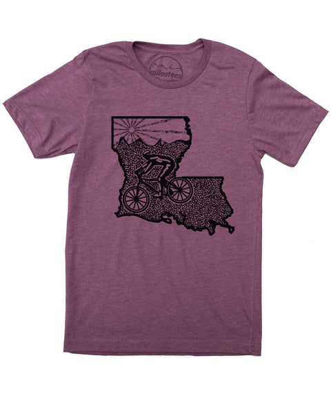 Black graphic on a plum tee. Design shows cyclist riding across Louisiana with rolling hills and a setting sun. Available in sizes S-XXL.  