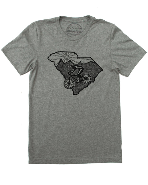 Hand-printed heather grey cycling t-shirt. Design features cyclist riding across South Carolina with a mountain logo and setting sun at the top of the State. (Sizes S-XL)
